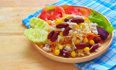 Healthy salad with fresh vegetables on wood background
