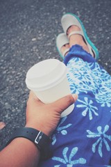 Selfie of coffee paper cup on hand with feet