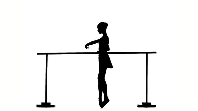 Ballerina posing on ballet barre. silhouette. slow motion