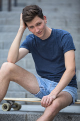 Young guy sitting on a longboard.