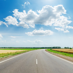 asphalt road under clouds with sun