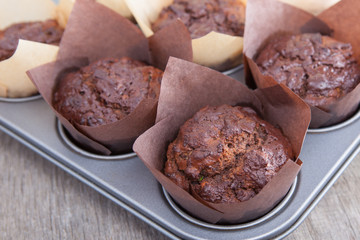 Flourless chocolate courgette muffins in a muffin tin, on a wooden table