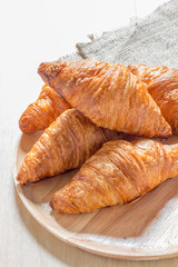 Croissant on wooden plate.