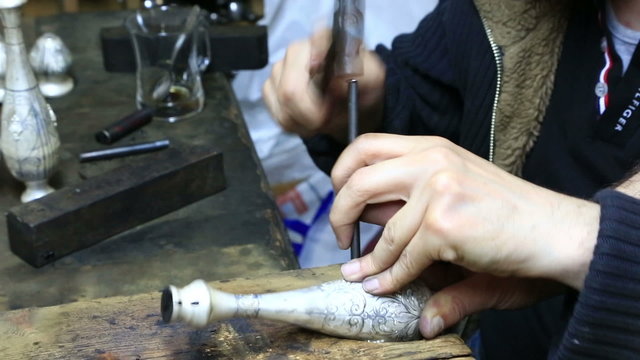 Professional engraver putting pattern on decorative vessel