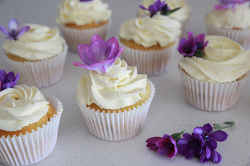 Homemade purple freesia flowers on vanilla cupcakes with whipped