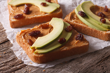 sandwiches with avocado, peanut butter and raisins close-up 
