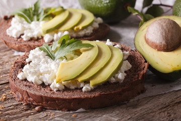 Healthy sandwiches with avocado, cream cheese and arugula close-up 

