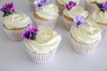 Homemade purple freesia flowers on vanilla cupcakes with whipped