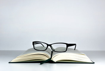 Open book and reading glasses an the table