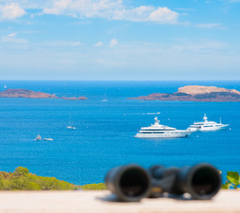 White paid telescope stands on sea coast over blue sky background