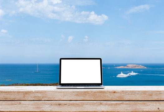 Laptop computer on wood table with sea background