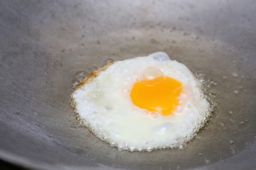 cooking fried egg in hot pan with oil