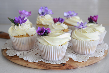Homemade purple freesia flowers on vanilla cupcakes with whipped