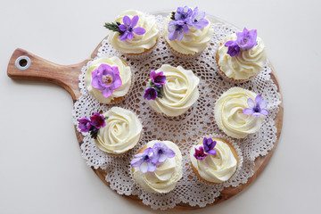 Homemade purple freesia flowers on vanilla cupcakes with whipped