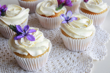 Homemade purple freesia flowers on vanilla cupcakes with whipped