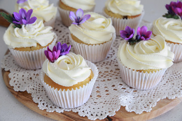Homemade purple freesia flowers on vanilla cupcakes with whipped
