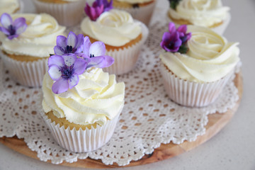 Homemade purple freesia flowers on vanilla cupcakes with whipped