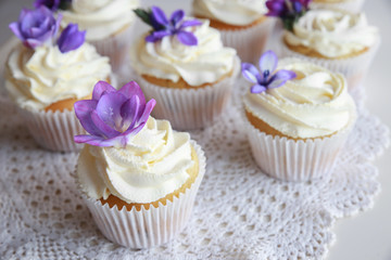 Homemade purple freesia flowers on vanilla cupcakes with whipped