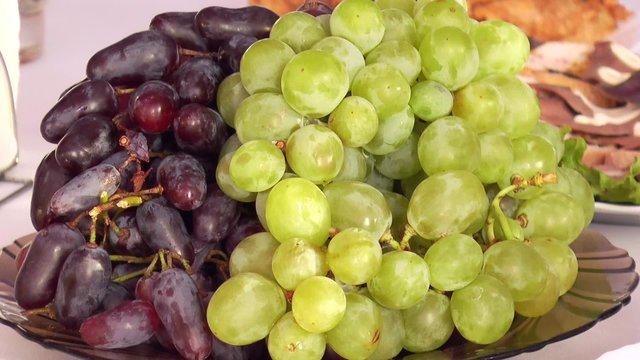 Green and red grapes on a platter on the table