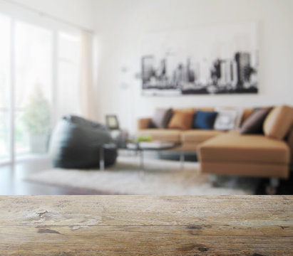 wooden table top with blur of modern living room interior as bac