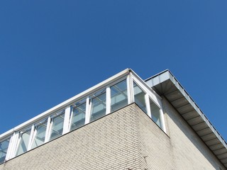 Klinkerfassade in Beige und Naturfarben mit verglaster Terrasse eines Penthouse vor blauem Himmel im Sonnenschein im Stadtteil Schildesche in Bielefeld im Teutoburger Wald in Ostwestfalen-Lippe