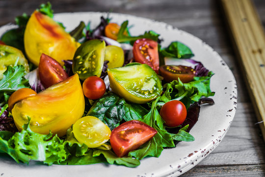 Fresh salad with spinach,arugula and heirloom tomatoes on rustic