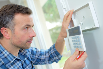 Electrician fitting an intrusion alarm