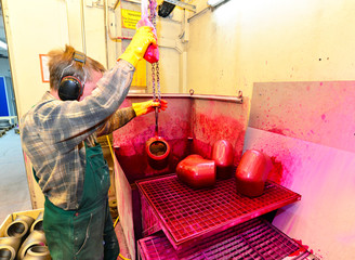 Arbeiter hebt Werkstücke mit Kran aus einem Tauchbad in der Industrie