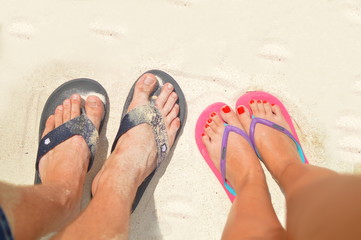 Fototapeta premium Couple walking with flip flops on the beach