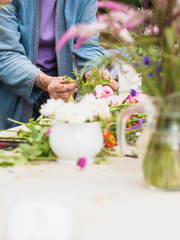 Hands of old woman arranging flowers.
