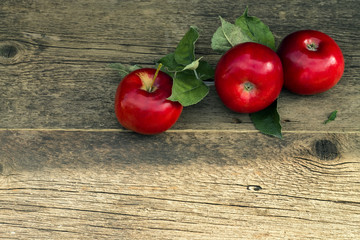 Three red apples on a wooden background