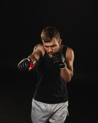 Fototapeta na wymiar Athletic bearded boxer with gloves on a dark background
