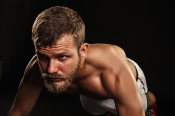 Obraz premium Athletic bearded boxer with gloves on a dark background