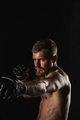 Athletic bearded boxer with gloves on a dark background