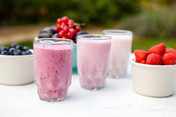 Three small glasses of smoothie on the white table in the garden