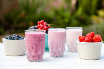 Three small glasses of smoothie on the white table in the garden