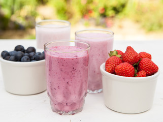 Three small glasses of smoothie on the white table in the garden