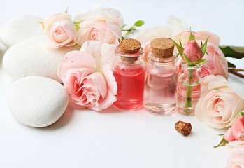 Beautiful rose flowers essential oils vials white stones spa background empty space