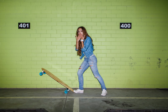 beautiful long-haired woman with a wooden skateboard near a gree