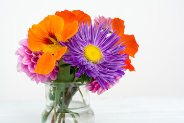 Colorful autumn flowers in the glass over white. Shallow focus. Horizontal composition, close-up.