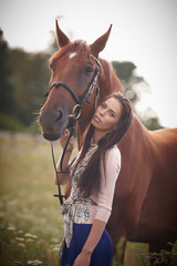Obraz premium Fashion woman with long brown hair posing with brown horse.