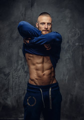 Fototapeta premium Muscular guy with beard putting out his sport shirt.