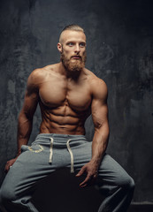 Fototapeta na wymiar Shirtless muscular man with beard in grey sports pants.