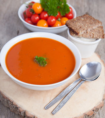 Tomato soup with frresh herbs, chilli, tomatoes and cream on the dark wooden table