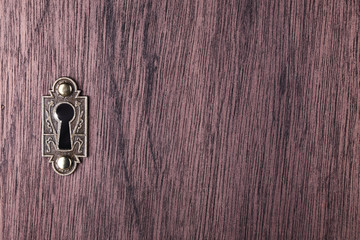A dark keyhole on a wooden door