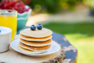Breakfast in the garden: pancakes with yoghurt and berries on a rustic table