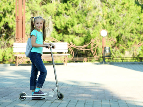 Small Girl Riding On Scooter In Park