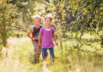 Fototapeta premium Little girl and boy playing together in sunny summer garden