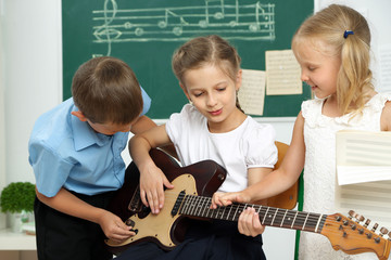 Cute pupils having music lesson in classroom at elementary school
