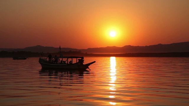 Boat with tourists on Irrawaddy river enjoying sunset, Bagan
